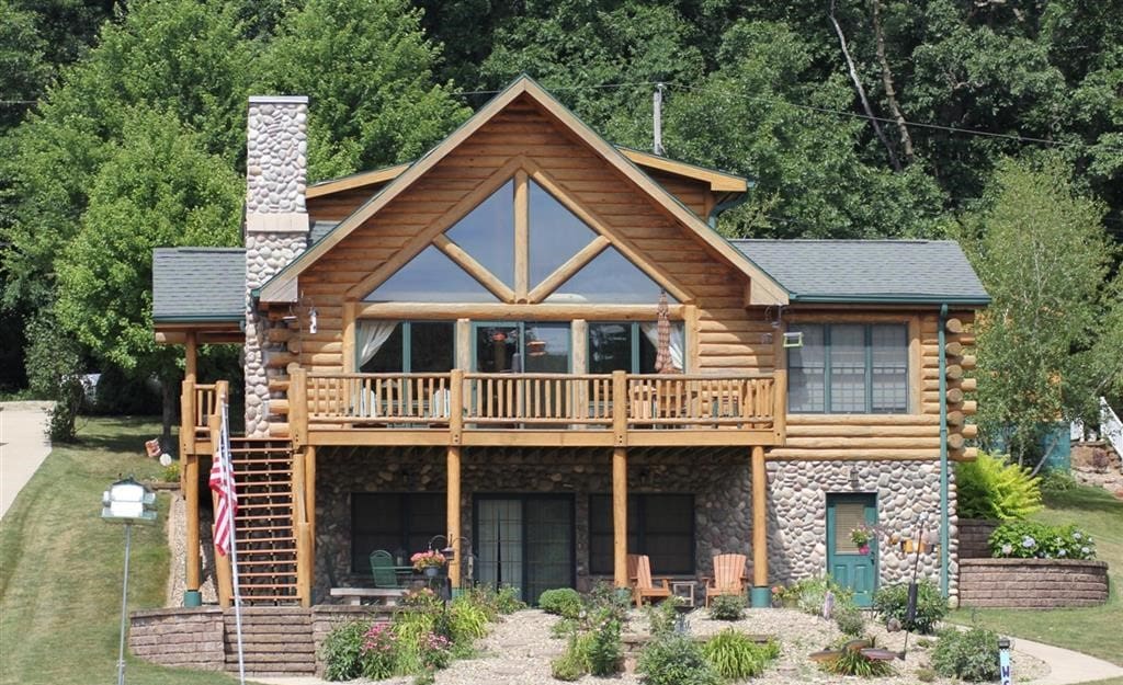 A large log home with a deck and stairs.