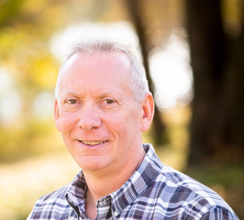 A man with white hair and a plaid shirt.