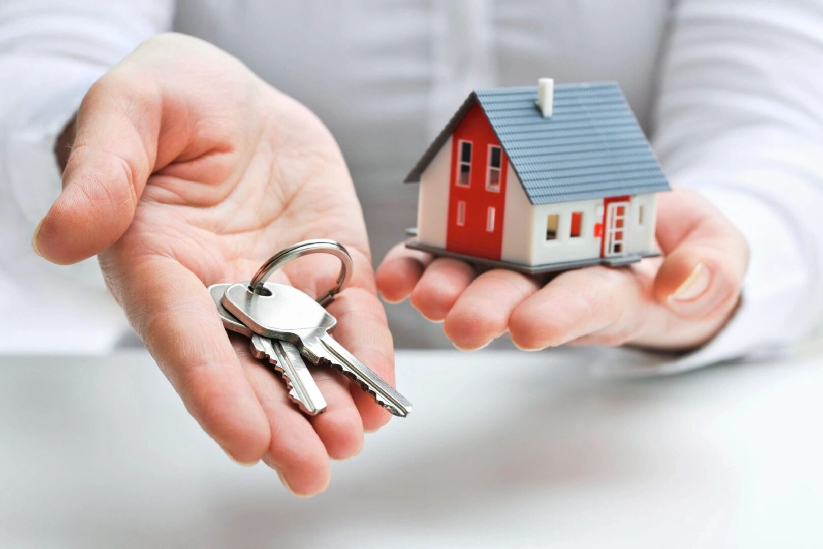 A person holding out their keys to someone 's house.